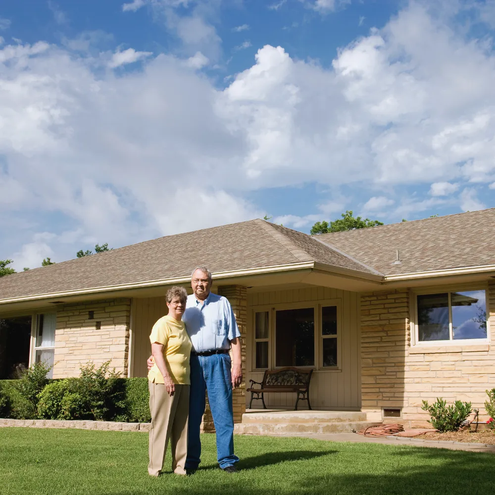 Happy couple posing for a photo outside of their home after having their windows replaced by Winchoice