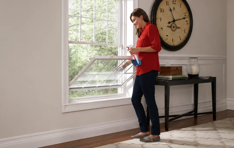 Homeowner cleaning the exterior glass of her WinChoice window, featuring tilting sashes